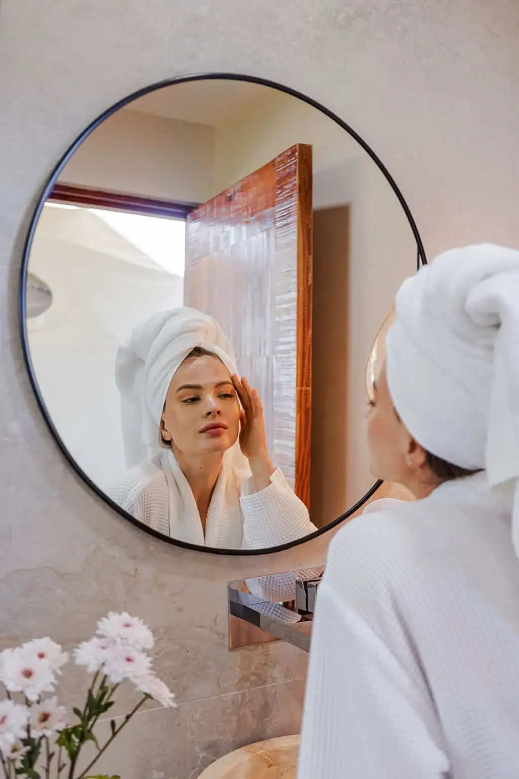 Mujer con bata blanca reflejada en espejo circular de hotel boutique