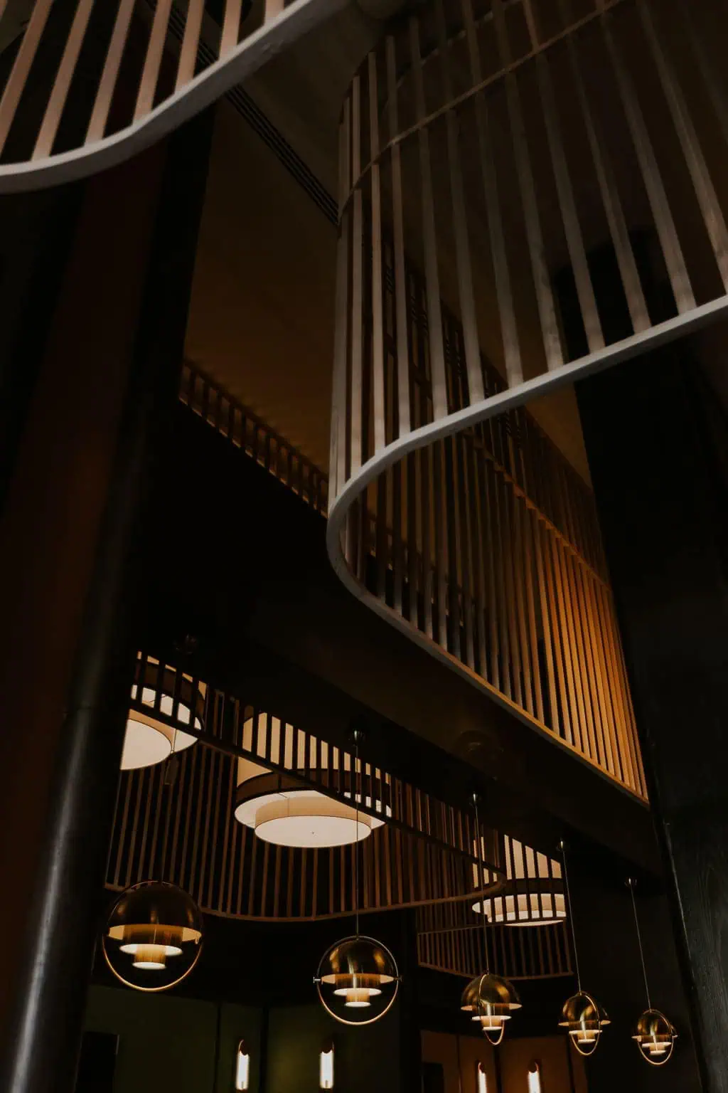 Lobby de hotel de lujo con escalera curva y lámparas doradas